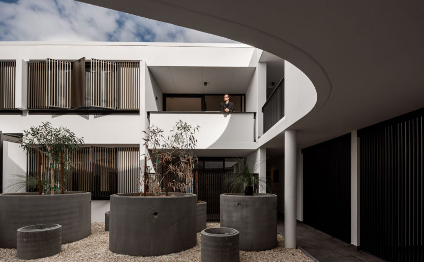 Architectural and Artistic shot of M/28 Apartment by Match courtyard with a resident standing on the first floor balcony